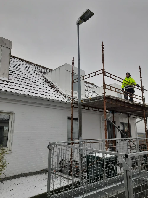 En man står och jobbar på en ställning och jobbar med taket